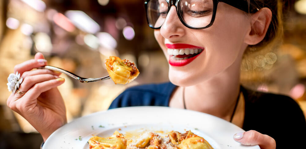 Young woman eating tortellini pasta