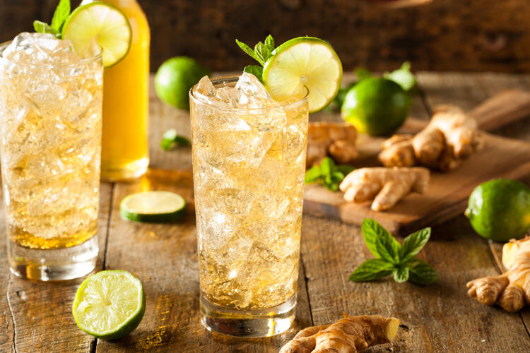 Deux verres de ginger beer maison, entourés de citron, gingembre et menthe