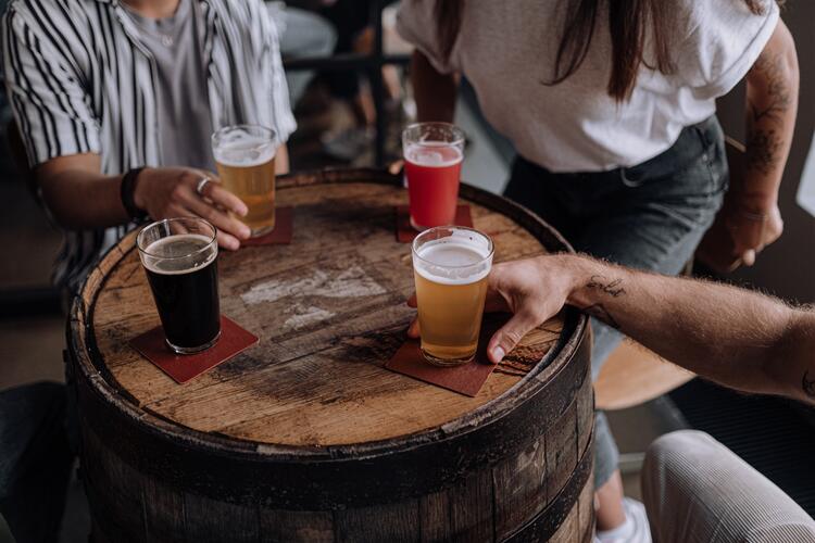 cuatro amigos tomando cerveza sobre barrica de madera