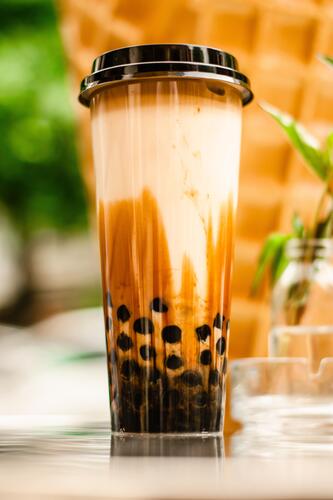 A tall glass of bubble tea with lid